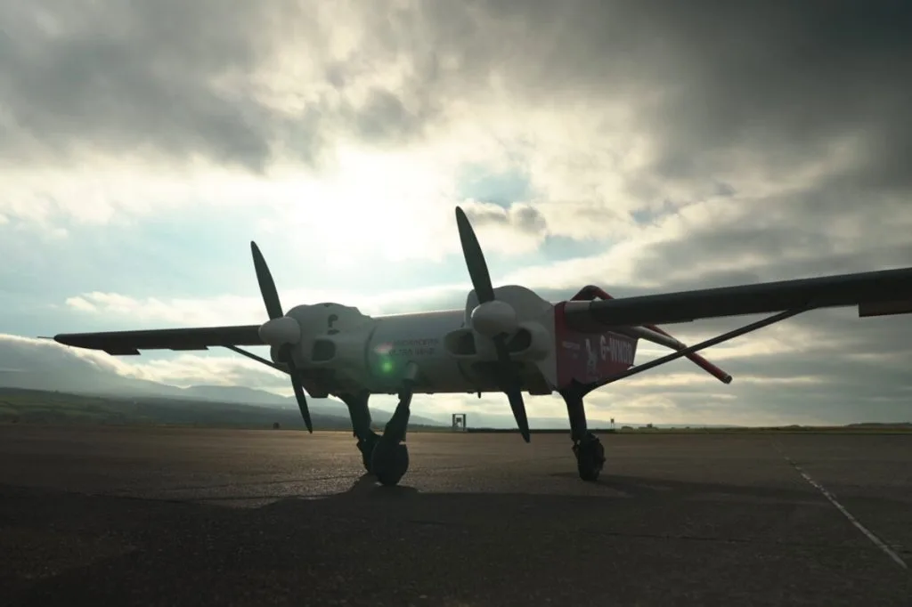 Windracers ULTRA autonomous heavy-lift cargo drone positioned on a runway with twin propellers, photographed from ground level against cloudy skies and distant hills.