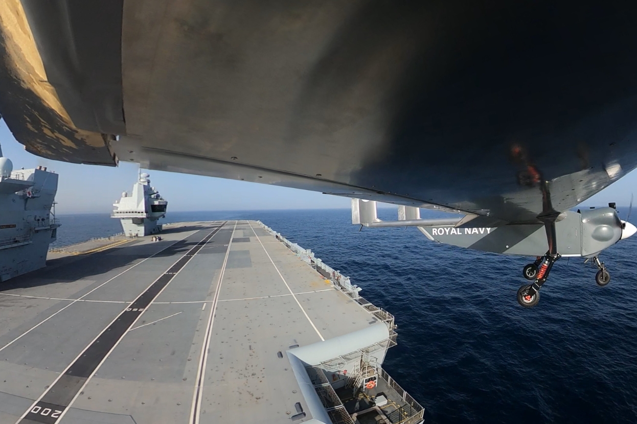Autonomous drone launch logistics: Drone operating from Royal Navy aircraft carrier flight deck at sea.